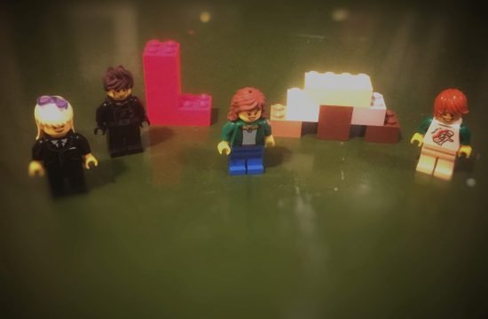 four lego minifigs and letters LM made of lego bricks